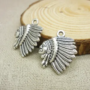 Macro shot of two vintage silver tribal chief charms with feather details on burlap