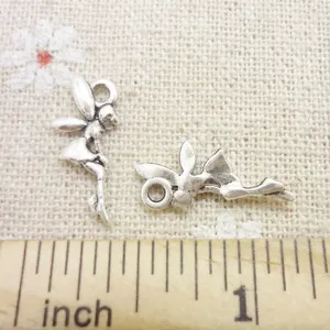 Detail of vintage silver angel pendants with wings on a textured background with ruler