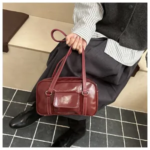 Close-up of a burgundy leather handbag with white stitching and stylish double handles