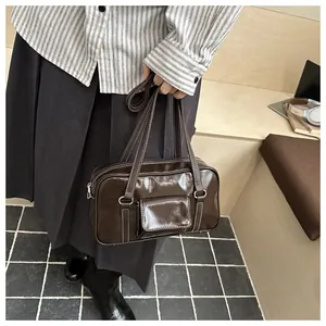 Detail of dark brown glossy leather handbag with white stitching and front pocket