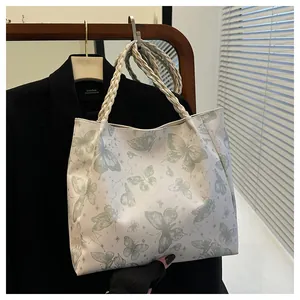 Detailed shot of white tote bag with green butterfly prints and woven rope handles