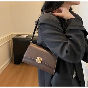 Detail of a dark brown matte leather baguette bag with a square golden metal buckle