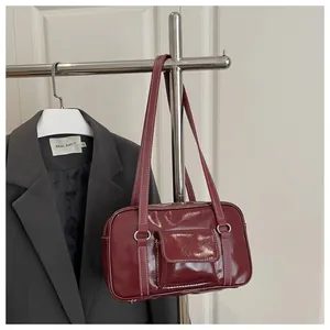 Detail of red glossy shoulder bag featuring white contrast stitching and front pocket