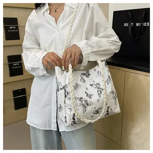 Detail view of white tote bag with black butterfly print and woven rope handles