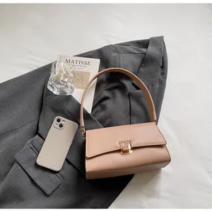 Detail of beige leather baguette bag with gold buckle on a stylish suit background