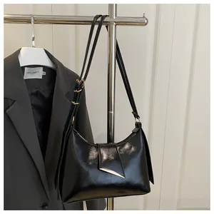 Détail du sac hobo noir brillant avec bandoulière réglable et ferrures dorées