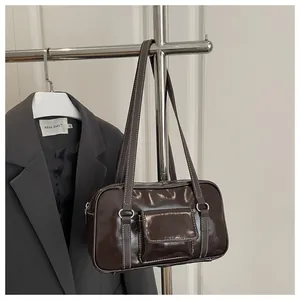 Detail of dark brown glossy patent leather shoulder bag with white contrast stitching