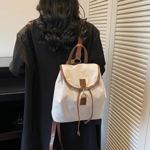 Chic cream canvas and brown leather backpack shown from a side view on a model