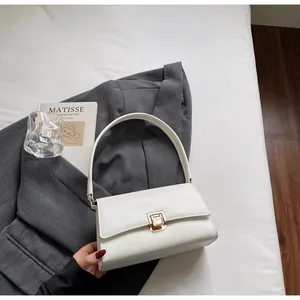 Detail of white PU leather baguette bag with premium golden square clasp on grey blazer