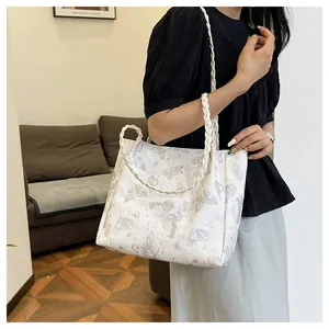 Detail of white tote bag featuring gray butterfly prints and woven rope handles