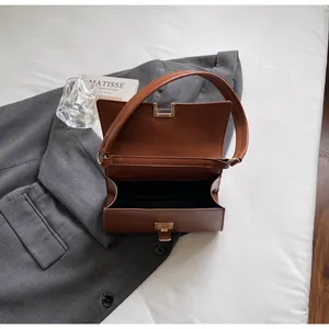 Detailed top view of retro brown baguette bag open on grey blazer with gold metal buckle