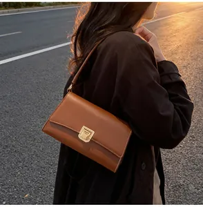 Detail view of caramel leather baguette bag with golden metal clasp in sunset light
