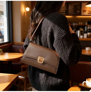 Detail view of dark brown leather baguette bag with square golden metallic clasp buckle