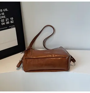 Detail of vintage brown leather crossbody bag with silver zipper and white text print