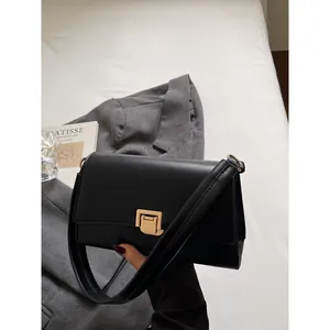 Minimalist black baguette shoulder bag with a vintage gold buckle and matte leather finish