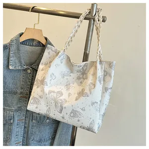 Close-up of white tote bag with butterfly patterns and woven rope shoulder straps