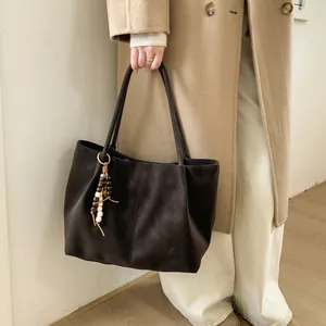 Detail of dark brown suede tote bag with wooden bead fringe tassel and long shoulder strap