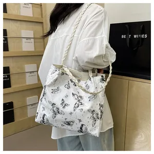 Detail of white tote bag featuring black butterfly prints and woven rope straps