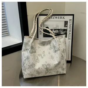 Detail of off-white tote bag with butterfly prints and woven leather handles
