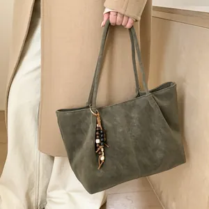 Detail of dark green suede tote bag featuring vertical stitching and vintage beaded tassel