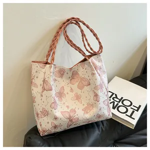 Detail of artistic pink butterfly print and woven leather handle on large tote bag