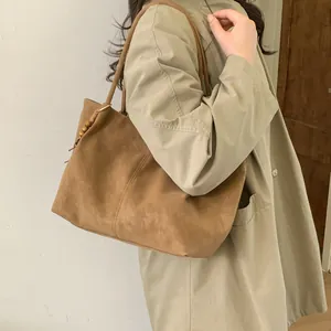 Detail of a brown suede tote bag with wooden bead accents on shoulder straps