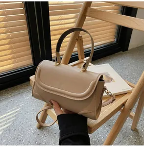 Detail einer beigen minimalistischen Handtasche mit runder Klappe und glatter Ledertextur
