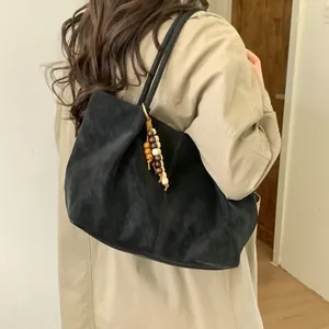 Fashionable black faux suede tote bag with wooden bead pendant shown on shoulder