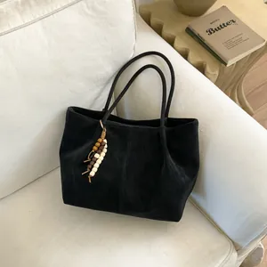 Detail of a black tote bag with matte texture and decorative beaded tassel charm