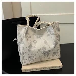 Detailed view of white tote bag with gray butterfly print and woven handles