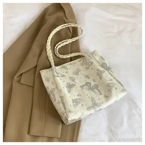Detail of light tote bag featuring grey butterfly prints and woven rope handles