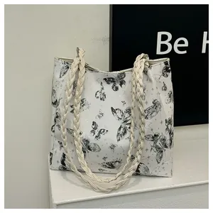 Detail of white tote bag with black butterfly prints and thick braided rope handles