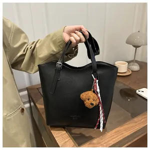 Détail du sac seau en cuir noir avec breloque ours et bandoulière réglable chic