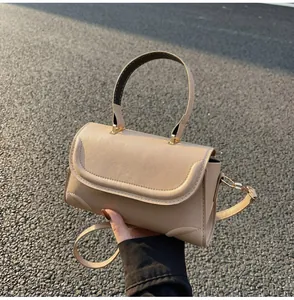 Detail einer beige Lederhandtasche mit goldener Schnalle auf Asphaltgrund