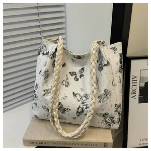 Detail of white tote bag featuring butterfly print and woven rope shoulder straps