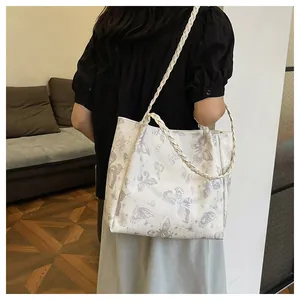 Detailed view of white tote bag featuring silver butterfly prints and braided straps