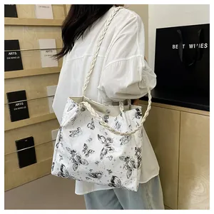 Detail of white tote bag with black butterfly print and braided rope shoulder strap