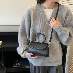 Minimalistische schwarze Umhängetasche aus Kunstleder mit Griff getragen von einem Model