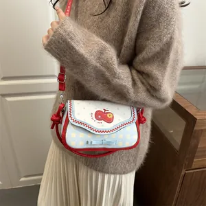 Detailed view of apple-shaped patchwork mini bag with red wavy trim and blue bow