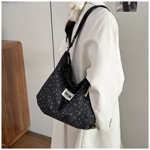 Detalle del bolso tote negro con estampado de lazos y etiqueta Swim en el hombro