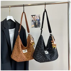Detalle de bolsos de lona con estampado de lazos, etiqueta lateral y colgante oso