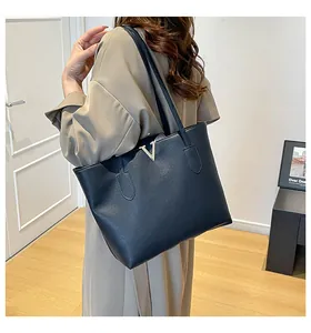 Detail der schwarzen Shopper-Tasche mit Litschistruktur und silbernem V-Metallakzent