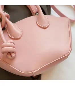 Détail du sac à main rose montrant le nœud iconique et la texture du cuir
