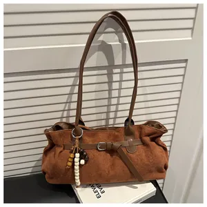 Gros plan d'un sac à bandoulière en daim caramel avec breloque perlée et boucle