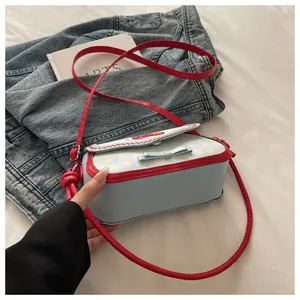 Detail shot of the red wavy lace trim and plaid pattern on the blue girls crossbody bag