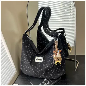 Detalle del bolso tote de pana negra con estampados de lazos y un tierno colgante de oso