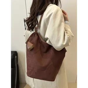 Sac seau en daim marron foncé avec mini pochette porté à l'épaule, vue de profil