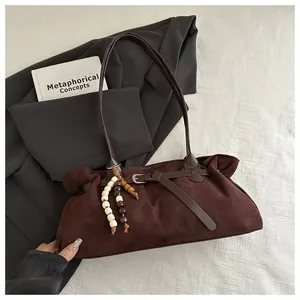 Détail d'un sac cabas en daim marron vintage avec pendentif perlé et boucle décorative