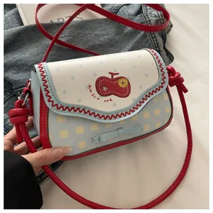Detail of blue lace patchwork shoulder bag with polka dots, embroidery and red strap