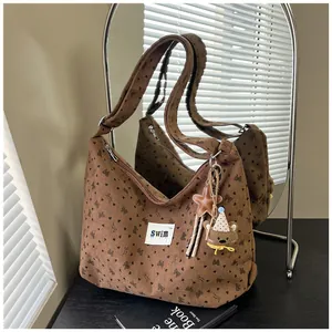 Detalle de bolso tote de pana marrón con estampado de corazones y colgante de osito